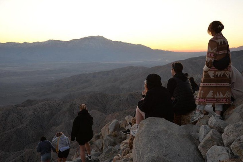 A group of people on a rocky mountain peak during sunset. 4