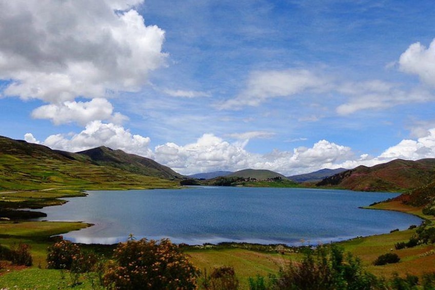A lake surrounded by hills, a clear sky, and a few clouds. 1