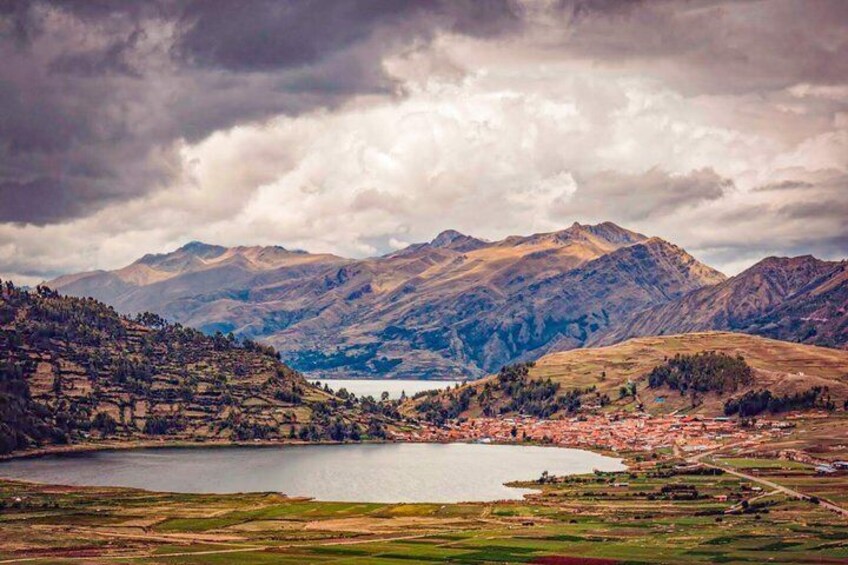 A mountainous landscape with a lake, a small town, and a clear sky. 1