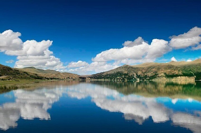 A calm lake with clear reflections of the sky and surrounding hills. 5