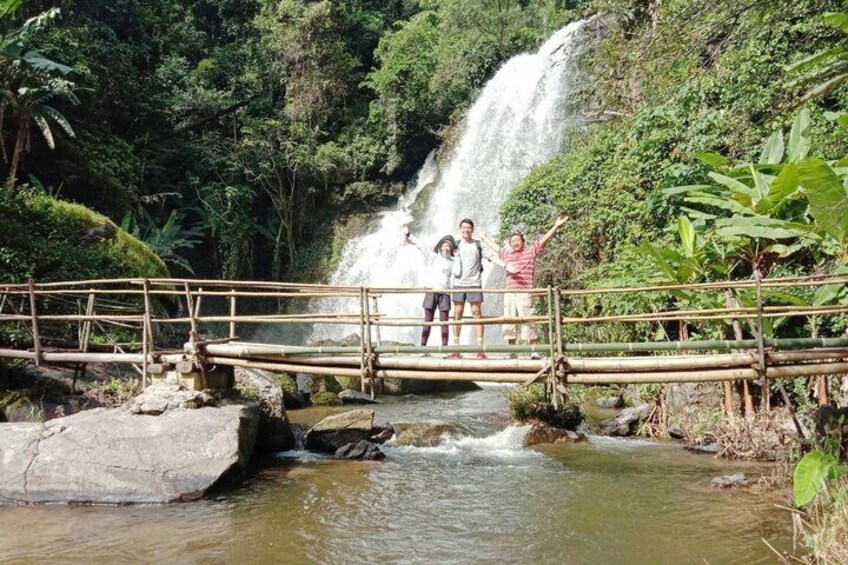 A wooden bridge over a river with a waterfall in the background. 4