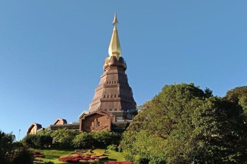 A large, multi-tiered temple with a pointed spire, surrounded by lush greenery and well-maintained gardens. 3