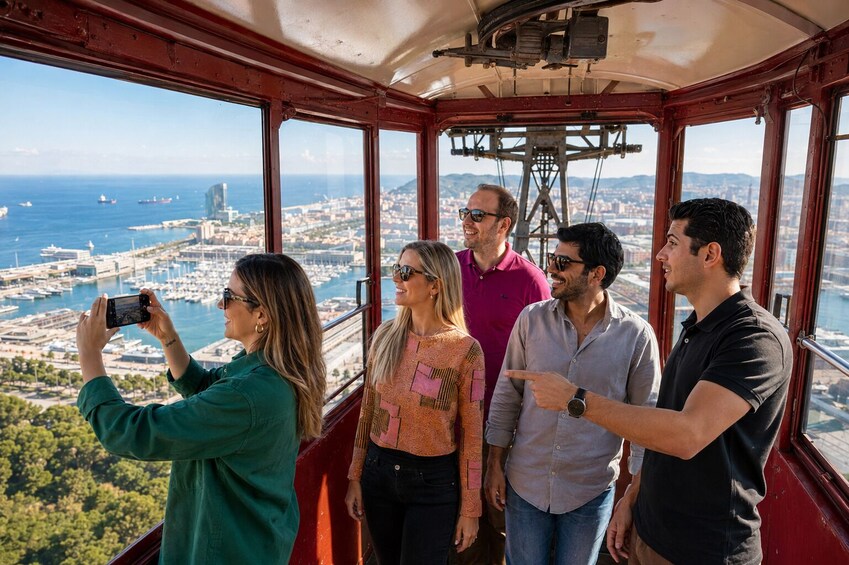A group of people on a cable car with a cityscape and port in the background. 1