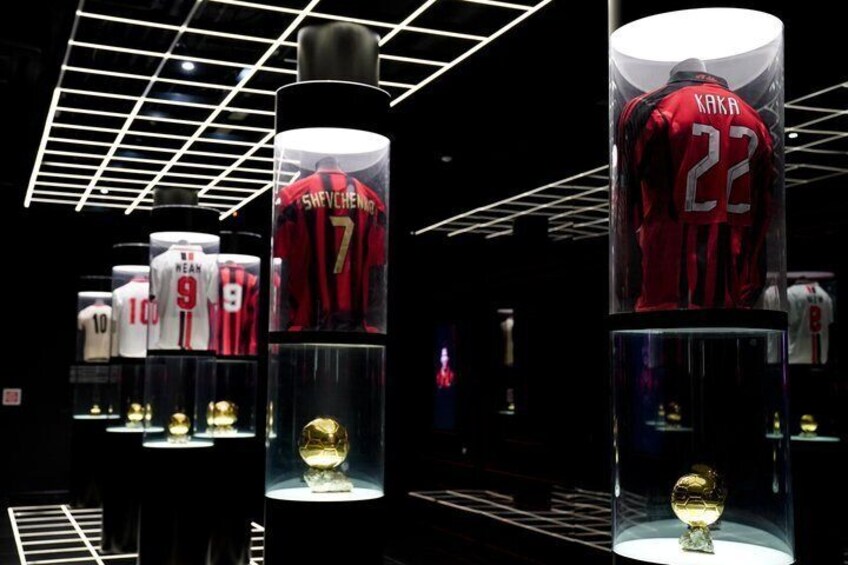 A display of football jerseys in glass cases with trophies. 3