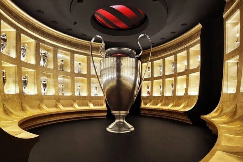 A trophy on a pedestal in a room with shelves of trophies. 1