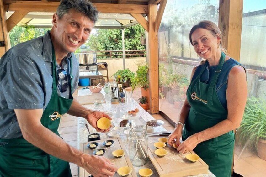 Two people preparing food outdoors with a table, cooking utensils, and ingredients. 1