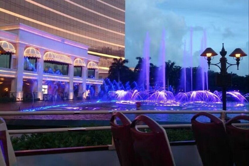 A fountain with water jets and illuminated arches in front of a building. 4