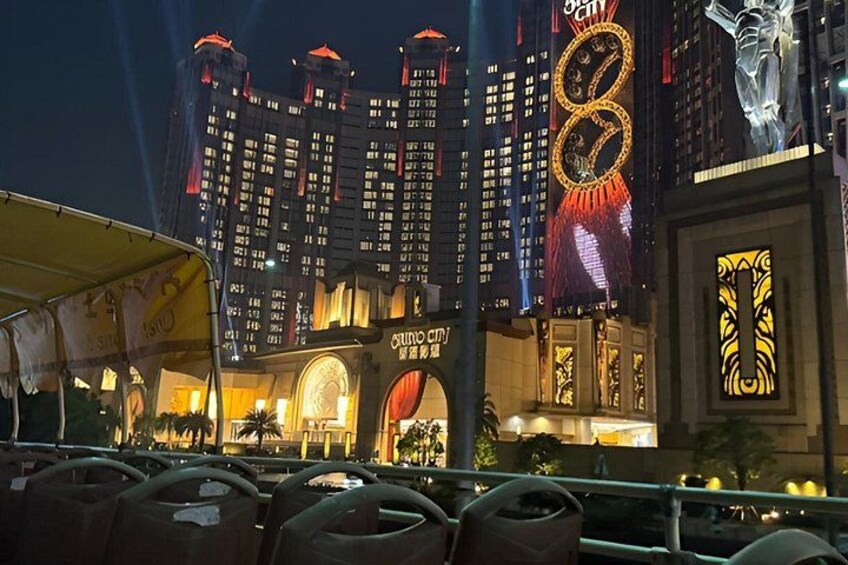 A brightly lit casino with a large sign and a statue. 2