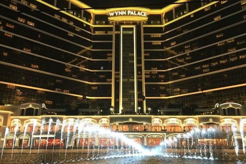 A grand building with a central tower and multiple balconies, surrounded by a water fountain. 3