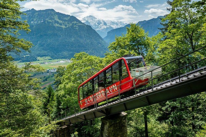 A red cable car on a bridge with a mountainous landscape in the background. 1