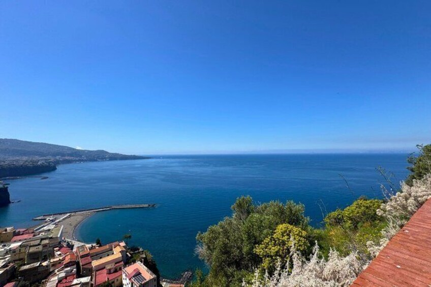 A coastal town with buildings, a pier, and a clear blue sea. 1
