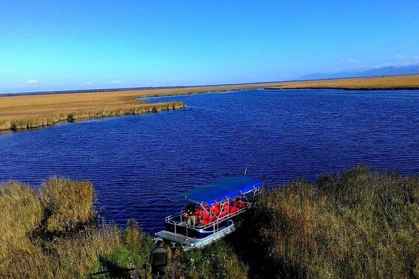 A boat on a calm river surrounded by grassy fields. 3