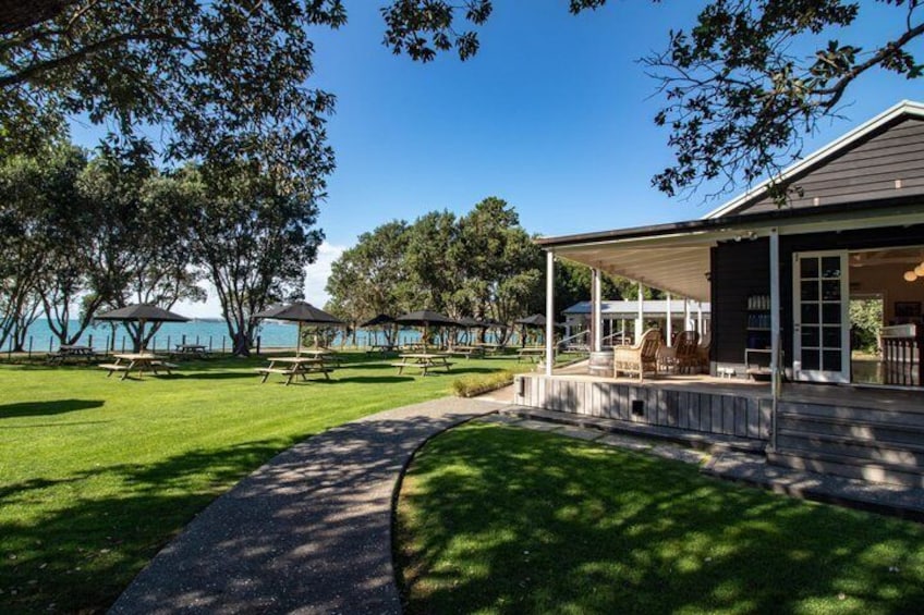 A waterfront property with a covered patio, picnic tables, and a lawn. 3