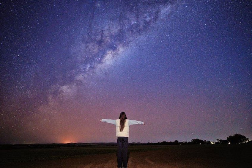 A person standing with arms outstretched under a starry night sky. 2