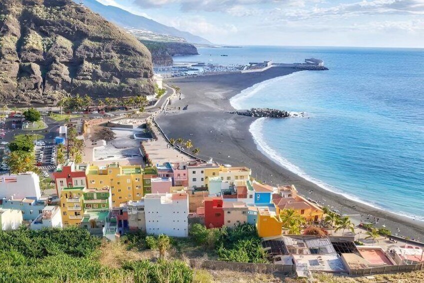 A coastal town with colorful buildings, a beach, and a rocky cliff. 3