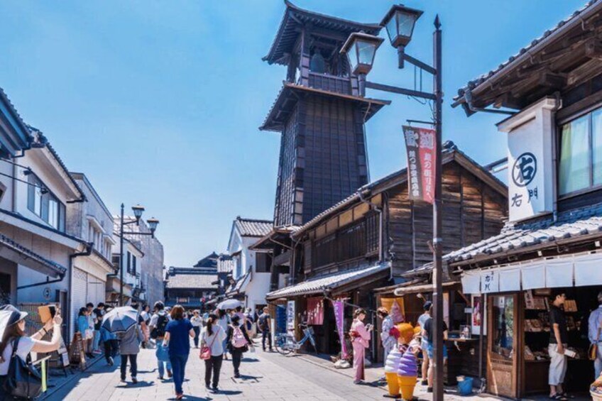 A bustling street with traditional buildings, pedestrians, and a prominent clock tower. 5