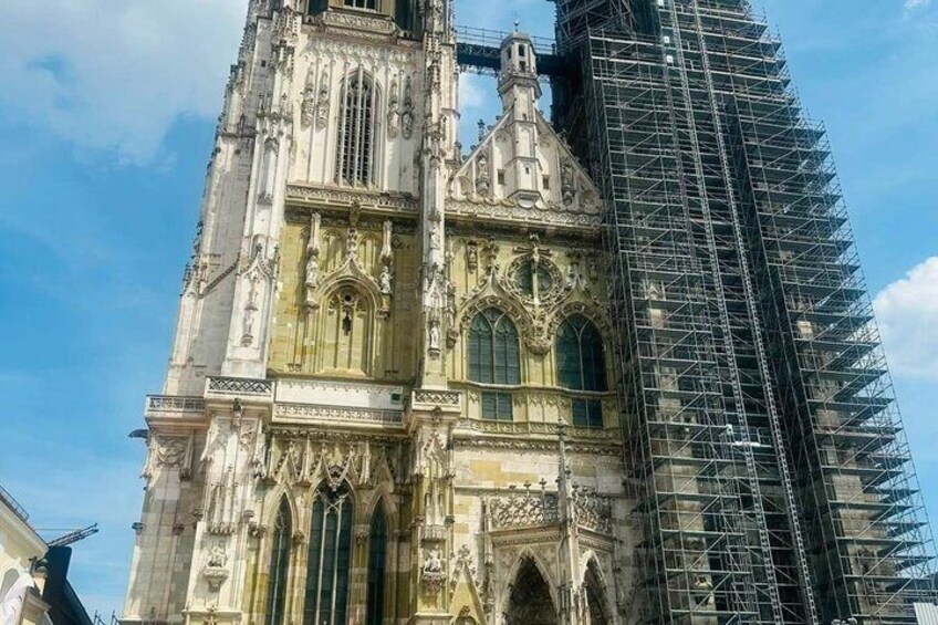 A historic cathedral with intricate architecture and a modern building under construction nearby. 3
