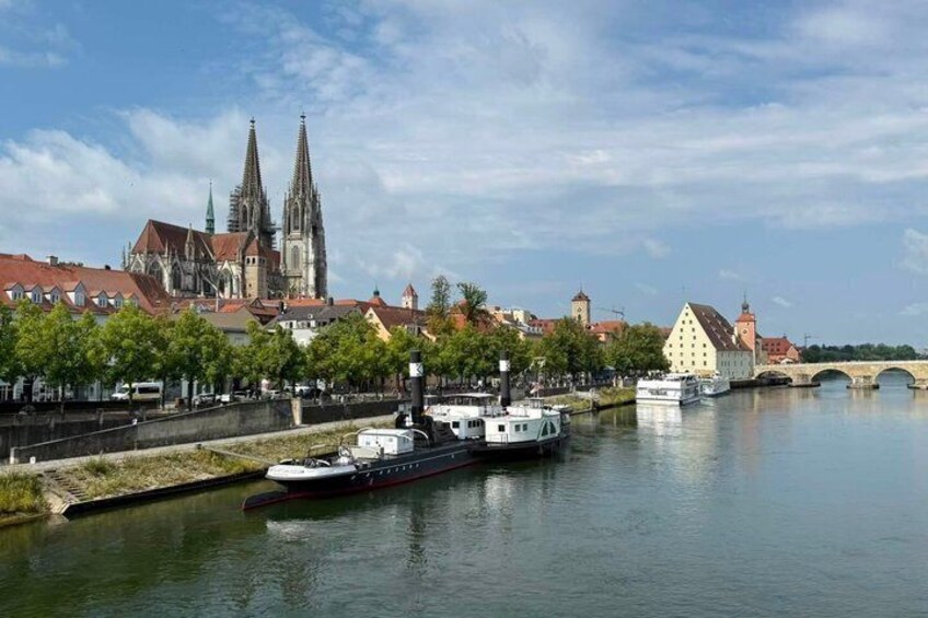 A river with boats, a bridge, and historic buildings including a cathedral. 1