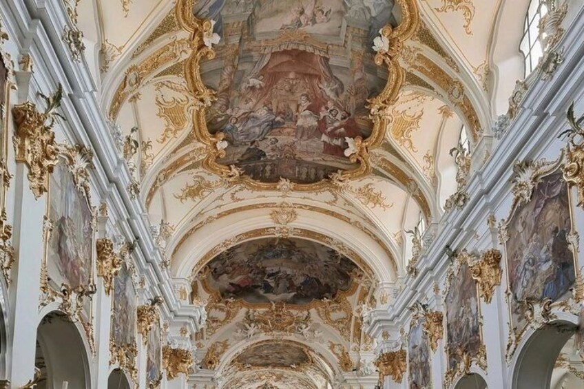 An ornate interior with elaborate ceiling frescoes and gold detailing. 4