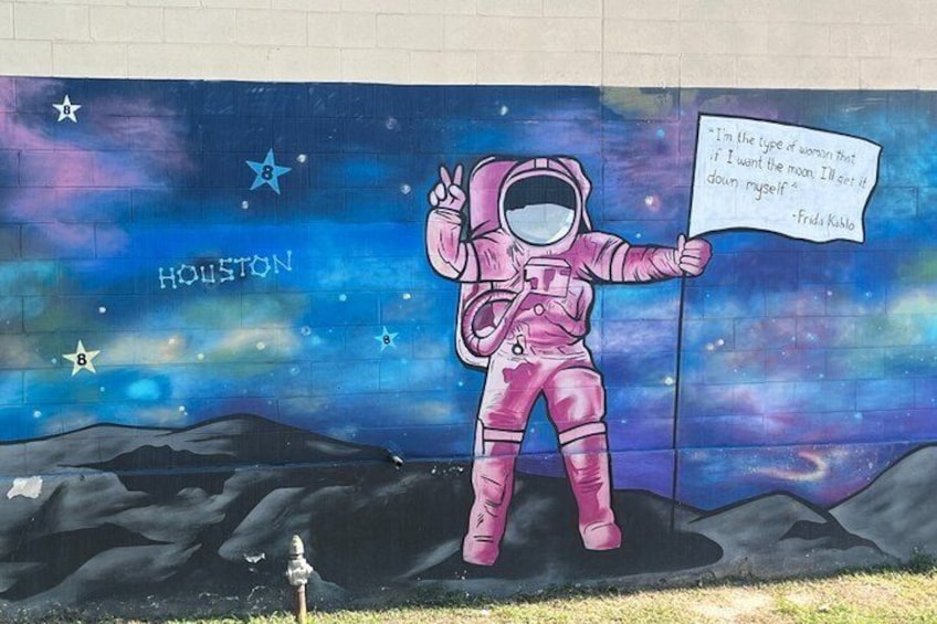 A mural of an astronaut with a sign, set against a starry night sky backdrop, with 'Houston' written on the left. 3