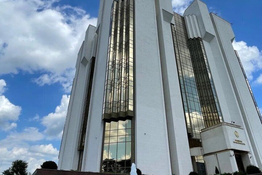 A tall, white building with large windows and a clear sky in the background. 4