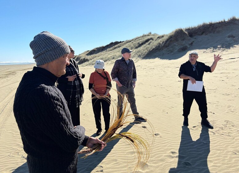A group of people on a sandy beach with dunes in the background. 4