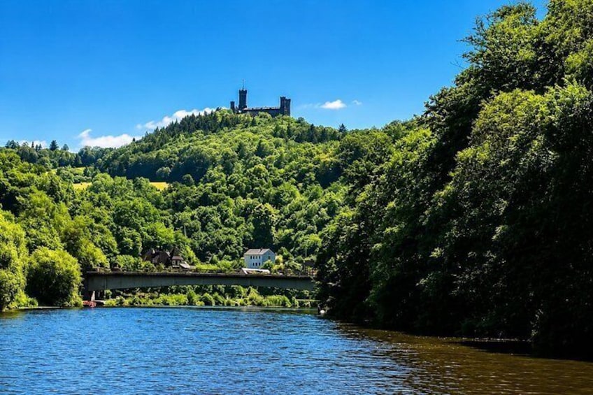 A river, a bridge, a hill with a castle, and dense greenery. 1