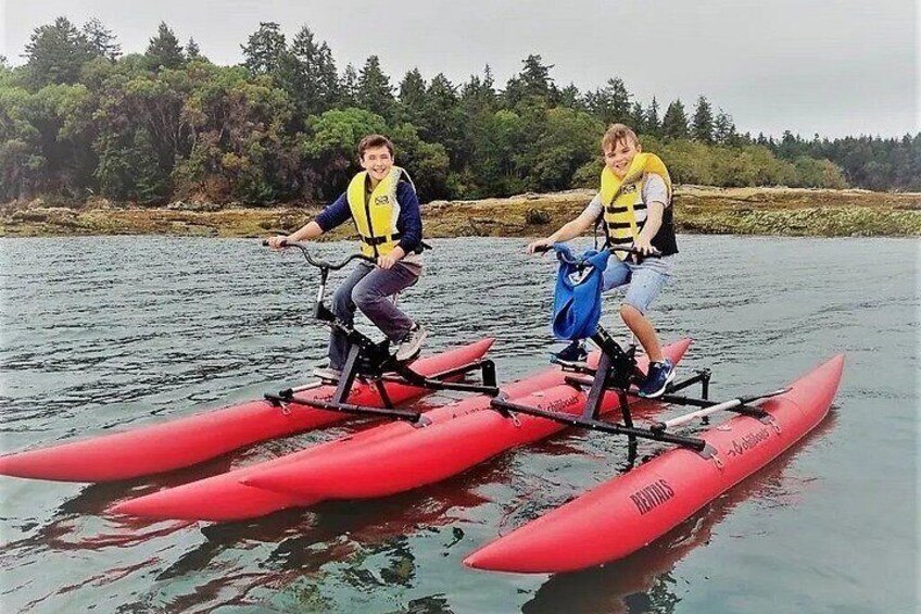 Two people riding a tandem bike on a red kayak. 2