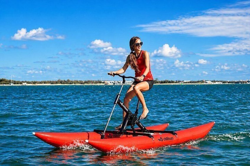 A person riding a red kayak on calm water with a clear sky and distant shoreline. 5