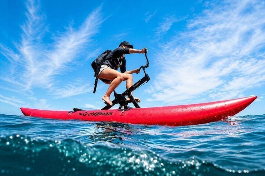 A person standing on a red kayak with the brand 'chillboats' on the side, paddling in the ocean under a clear blue sky. 4