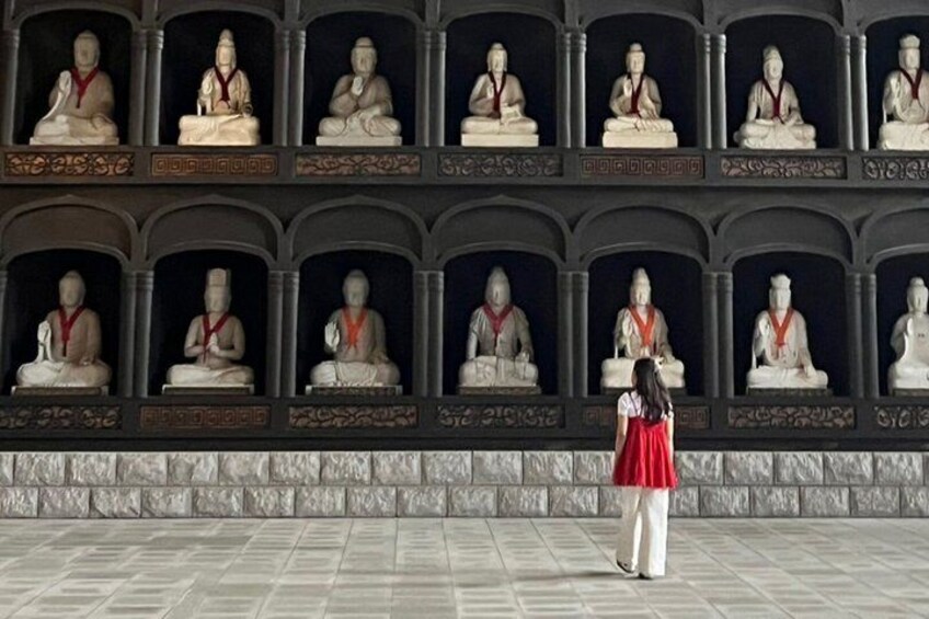 A person standing in front of a wall of statues. 1