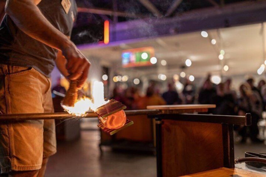 A person lighting a candle on a table in a public indoor space. 1