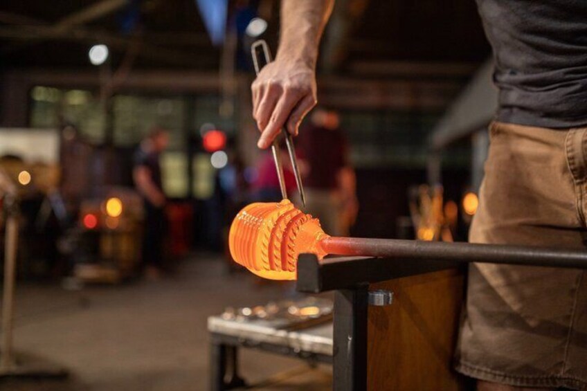 A person working with a glowing orange object on a metal stand in an industrial setting. 5