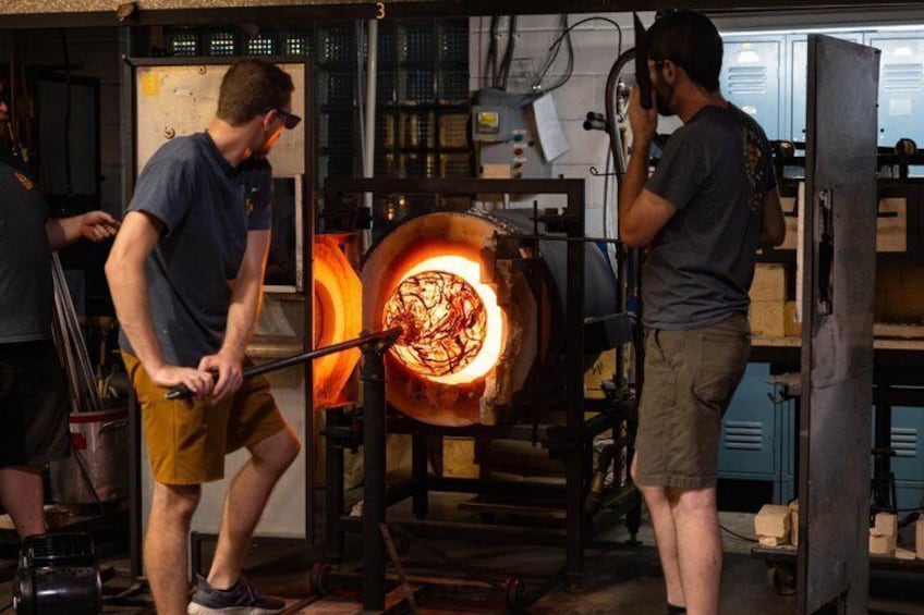 Two individuals working with a large industrial furnace. 3