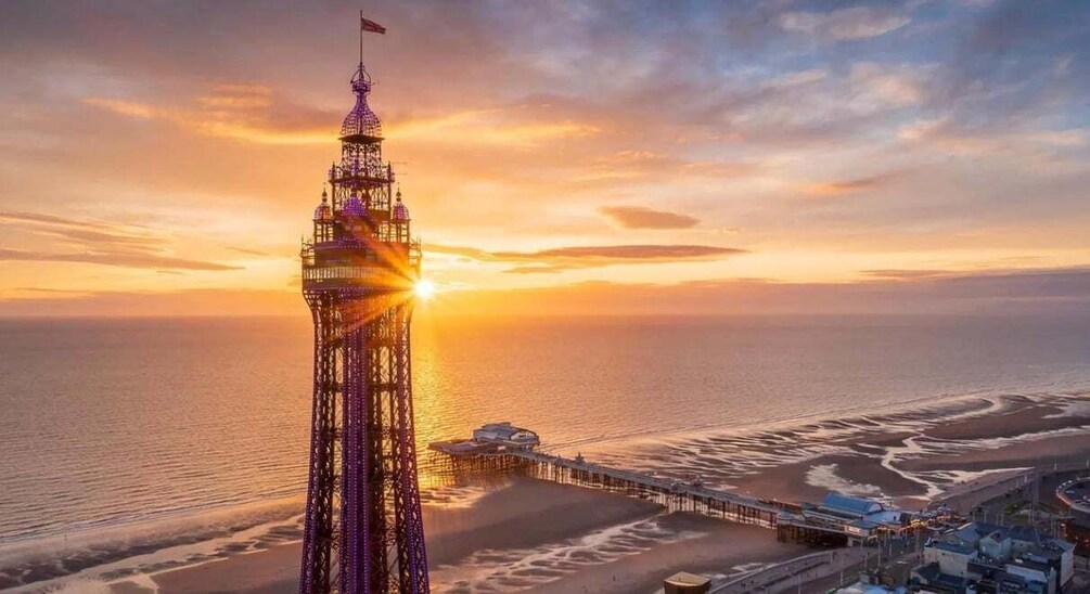 A tall tower with a flag, a pier extending into the water, and a sunset over a beach. 4