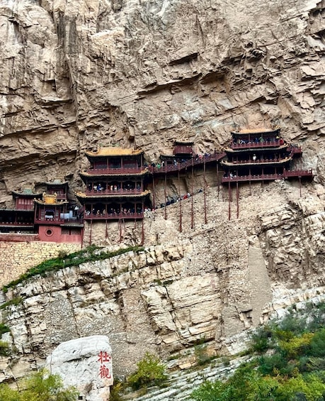 A series of traditional multi-tiered buildings built into a cliffside. 2