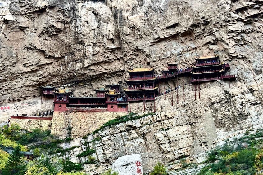 A traditional multi-tiered temple built into a cliffside. 1