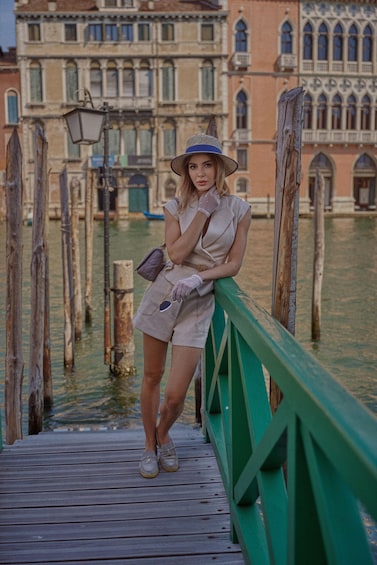 A woman standing on a wooden bridge with a historic building in the background. 3