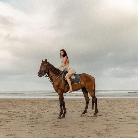 A person riding a horse on a beach with the ocean in the background. 4