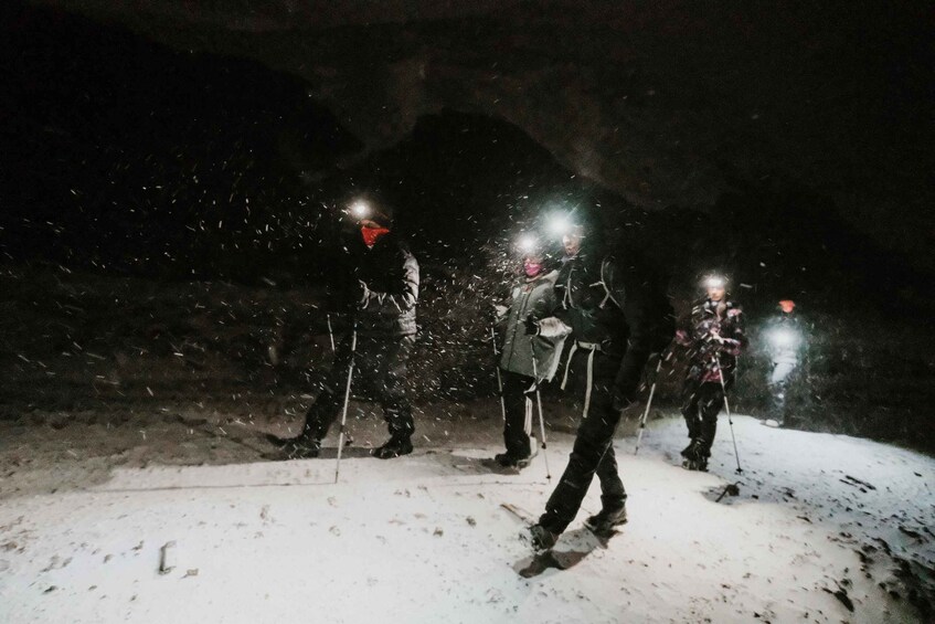 People walking in the snow at night with flashlights. 1