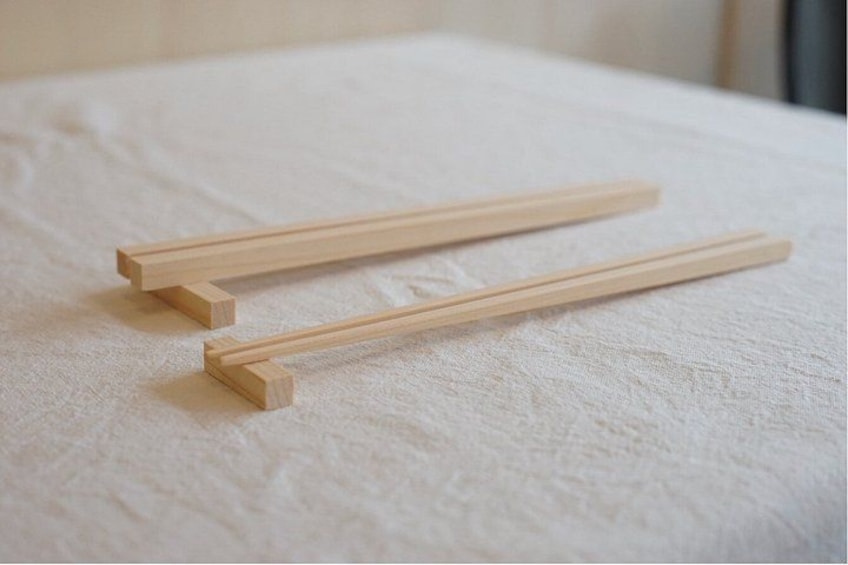 Two wooden chopsticks lying on a textured fabric surface. 3