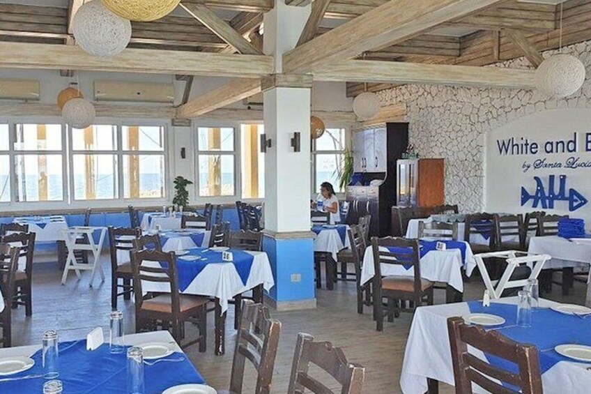 A restaurant with tables set for dining, a stone wall, and a sign reading 'White and Blue.' 5