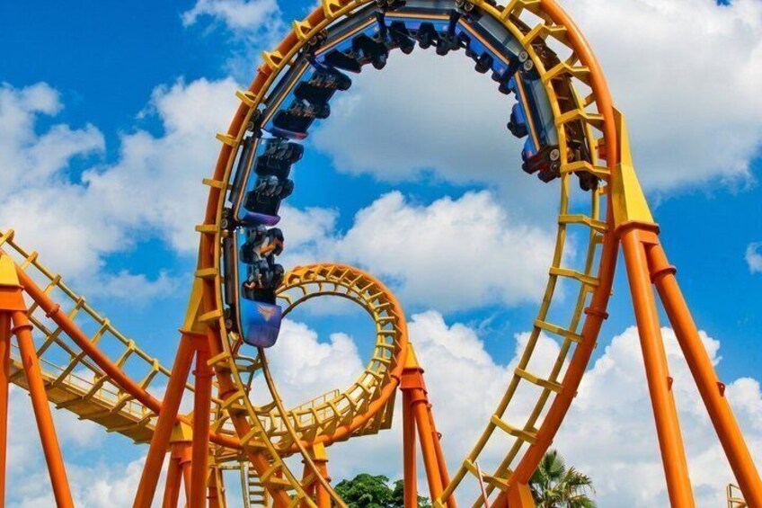 A roller coaster with a loop against a blue sky with clouds. 4