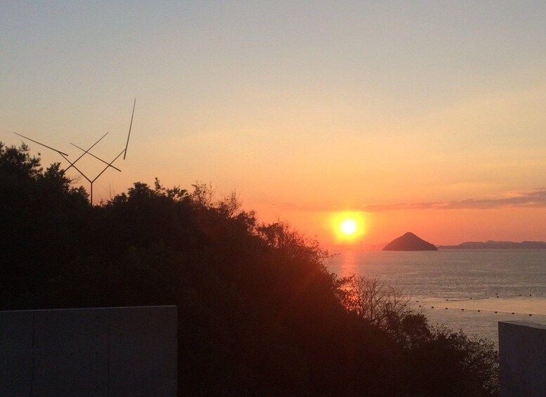 A sunset over a body of water with silhouetted landforms and a clear sky. 3