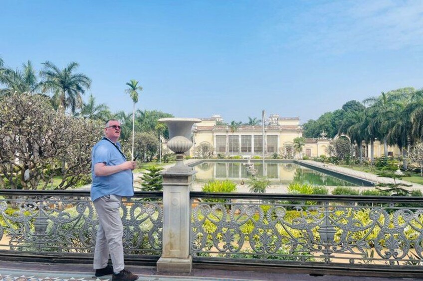 A man standing on a bridge with a fountain and a building in the background. 3