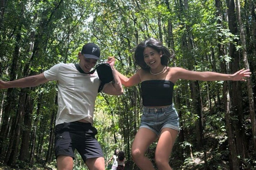 Two people dancing in a forest with tall trees. 3