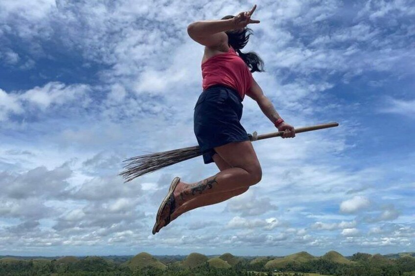A person jumping with a broom in mid-air against a cloudy sky. 5
