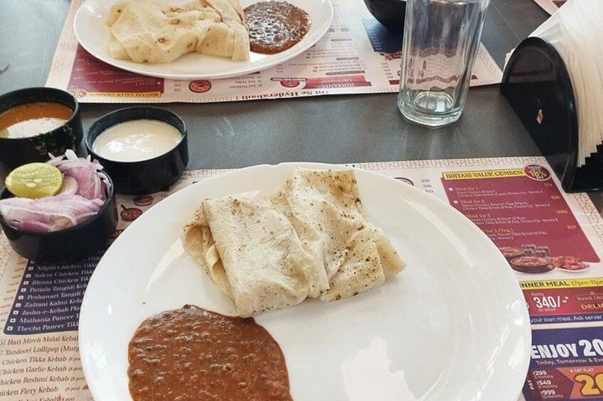 A plate of food with a glass of water and a menu. 3