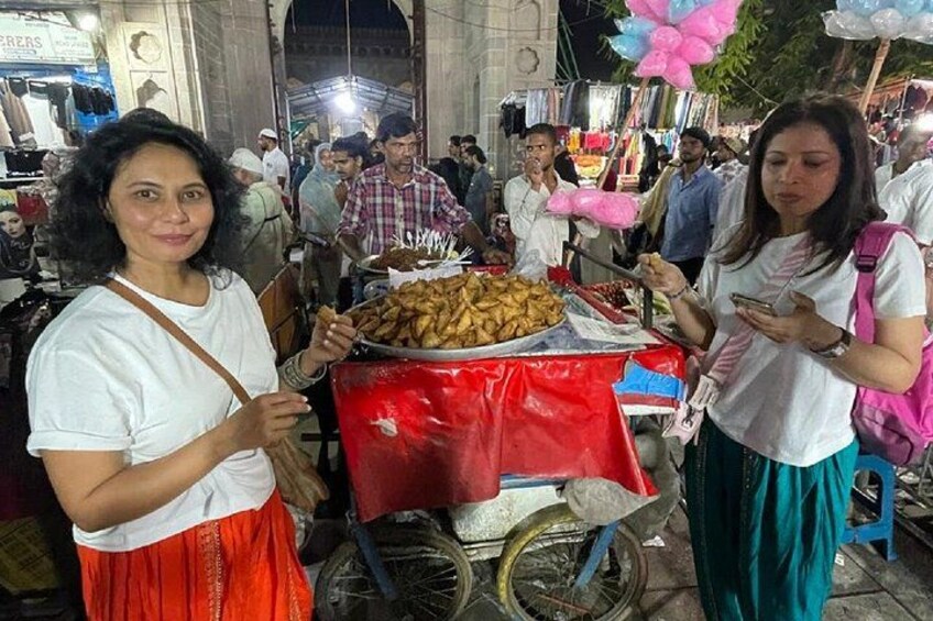 A street market with food stalls and people. 1