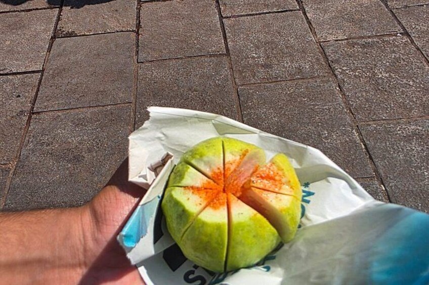 A hand holding a paper bag with a halved fruit, possibly a melon, on a paved surface. 5